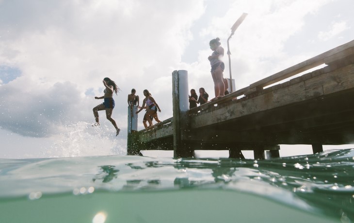 Children jumping off a pier into the water. 